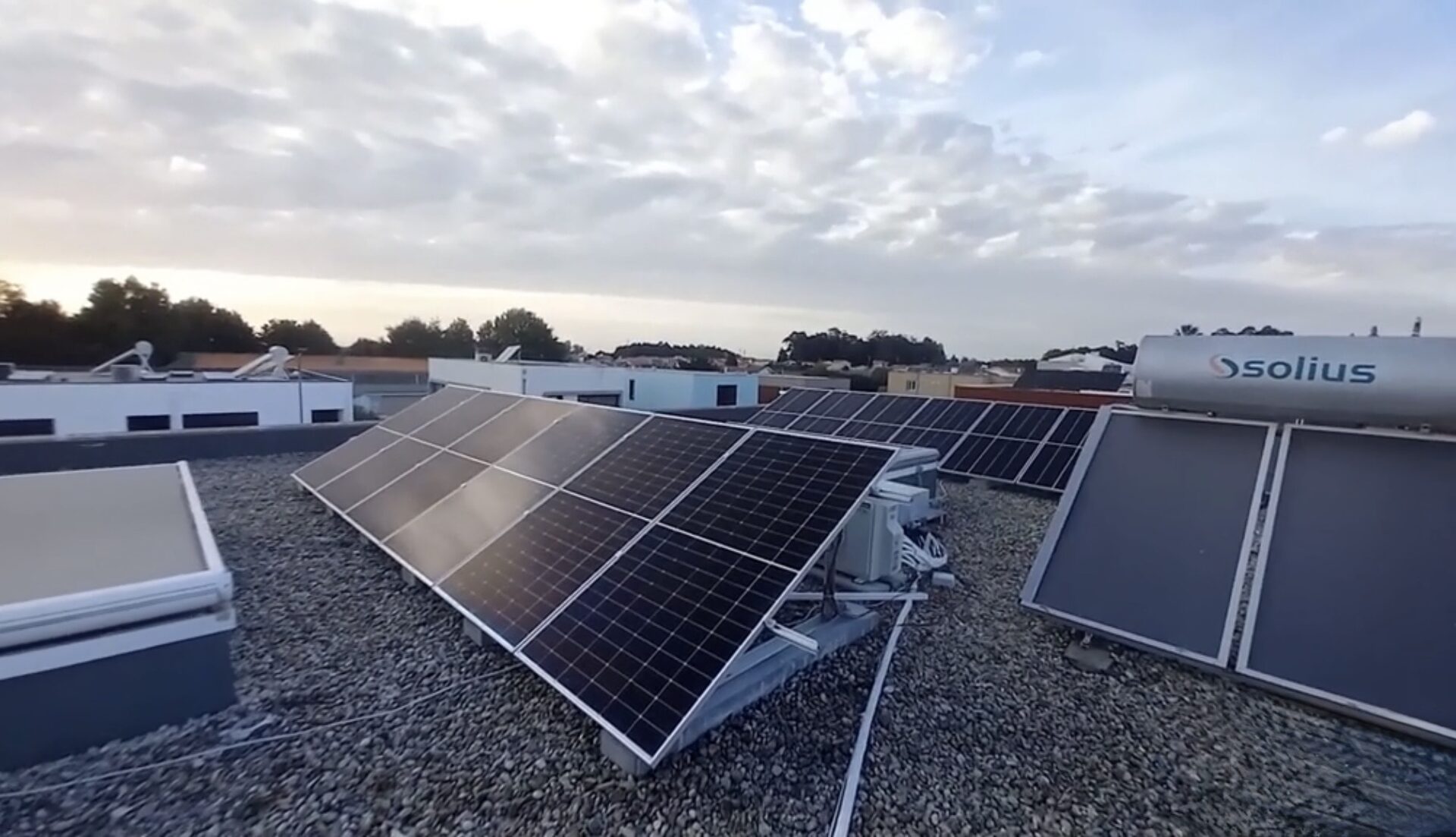 Cobertura plana com painéis solares e termossolar ao pôr do sol